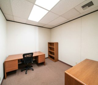 an empty room with a desk and a book shelf